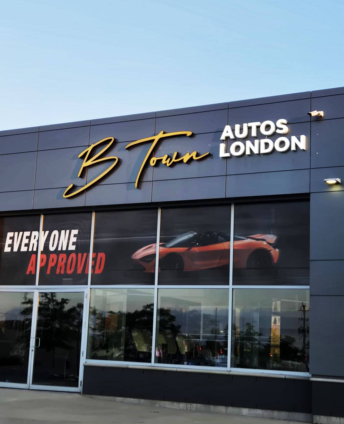 Car dealership with script and block letters on the fascia and printed window graphics